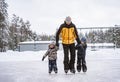 Cute little boys learning to skate on a rink with their father