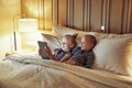 Little brother and sister smiling while watching videos in bed Royalty Free Stock Photo