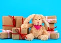 Cute little brown plush rabbit and a stack of boxes wrapped in brown kraft paper and tied with silk ribbon Royalty Free Stock Photo
