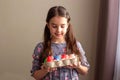 A cute little brunette girl holds a cardboard tray with colorful eggs