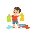 Cute little bully boy standing among scattered clothes, hoodlum cheerful little kid, bad child behavior vector