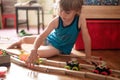 Cute little candid five year old kid boy playing at home with children`s toys cars and the wooden road on a floor of room in a co Royalty Free Stock Photo