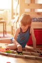 Cute little candid five year old kid boy playing at home with children`s toys cars and the wooden road on a floor of room in a co Royalty Free Stock Photo