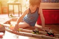 Cute little candid five year old kid boy playing at home with children`s toys cars and the wooden road on a floor of room in a co Royalty Free Stock Photo