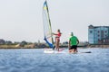 Cute little caucasian blond child girl enjoy having fun learning to surf on winsurfing board at freshwater pond lake or