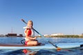 Cute little caucasian blond child girl enjoy having fun sitting on sup board surfing at freshwater pond lake or river Royalty Free Stock Photo