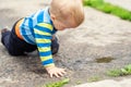 Cute little caucasian blond toddler boy having fun lying in a puddle after rain outdoors. Curious child discovering Royalty Free Stock Photo