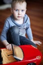 Cute little caucasian boy, blond with blue eyes, plays with a toy - red car, sitting on the floor. Beautiful child. Royalty Free Stock Photo