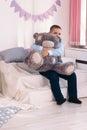 little caucasian boy hugs big gray teddy bear