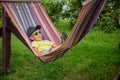 Cute little Caucasian boy relaxing and having fun in multicolored hammock in backyard or outdoor playground. Summer active leisure