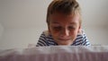 Cute little caucasian boy 10 years old lies at home on the bed in the bedroom and smiles slyly, squinting and closing Royalty Free Stock Photo