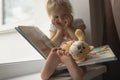 Cute little caucasian child sits near window and reads book. Royalty Free Stock Photo