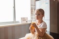 Cute little caucasian girl with blonde hair sitting on the kitchen table and drinking fresh mango juice. Healthy lifestyle concept Royalty Free Stock Photo