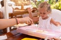 Cute little Caucasian girl eating spaghetti at table sitting in child seat outdoor restaurant Royalty Free Stock Photo