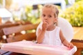 Cute little Caucasian girl eating spaghetti at table sitting in child seat outdoor restaurant Royalty Free Stock Photo