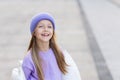 Cute little caucasian girl eight years old with blonde hair smiling outdoor. Kid wearing stylish shirt and knitted hat Royalty Free Stock Photo