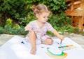 Cute little caucasian Girl enjoying Painting at the backyard with paper, water colour and art brush. Selective focus Royalty Free Stock Photo