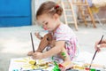 Cute little caucasian Girl enjoying Painting at the backyard with paper, water colour and art brush. Selective focus Royalty Free Stock Photo