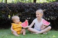 Cute little caucasian girl and her baby sister eating watermelon outdoor at hot summer day. Kids siblings spending time Royalty Free Stock Photo