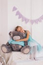 little caucasian girl hugs big gray teddy bear