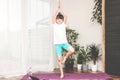 Cute little caucasian girl is practicing yoga at home. The child stands in one of the assanas. Sports, workout and fitness at home Royalty Free Stock Photo
