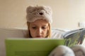 Cute little caucasian girl in pyjama reading a book. Kid sitting on a bed in the room. Stay at home during coronavirus covid-19