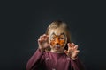 Cute little caucasian girl with tiger face painting on the black background. Close up portrait of little kid with face-painting.