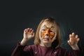 Cute little caucasian girl with tiger face painting on the black background. Close up portrait of little kid with face-painting.