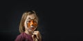 Cute little caucasian girl with tiger face painting on the black background. Close up portrait of little kid with face-painting. Royalty Free Stock Photo