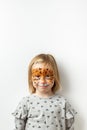 Cute little caucasian girl with tiger face painting on the white background. Close up portrait of little kid with face-painting. Royalty Free Stock Photo