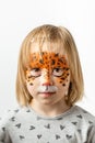 Cute little caucasian girl with tiger face painting on the white background. Close up portrait of little kid with face-painting. Royalty Free Stock Photo