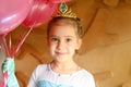 Cute little caucasian seven year old children girl at home in a costume elsa frozen with a golden crown and pink balloons cheerfu