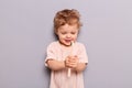 Cute little child baby brushing teeth isolated over gray background holding looking at toothbrush with curious happy face learning Royalty Free Stock Photo