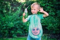 Cute little child boy in avocado costume drinking green juice or smoothie on backyard. Vegan, sustainable lifestyle, healthy