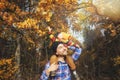 Cute little child boy sitting on his father`s shoulders on background of golden autumn trees in forest. Time together dad and son Royalty Free Stock Photo