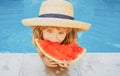 Cute little child boy in the swimming pool eating watermelon. Enjoy eating tropical fruit. Summer kids concept. Happy Royalty Free Stock Photo