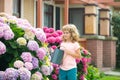 Cute little child boy watering plants with a watering can in the garden. A charming little kid helping his parents grow Royalty Free Stock Photo