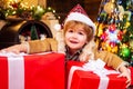 Cute little child is decorating the Christmas tree indoors. Happy little child dressed in winter clothing think about Royalty Free Stock Photo