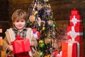 Cute little child is decorating the Christmas tree indoors. Happy little child dressed in winter clothing think about Royalty Free Stock Photo