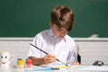 Cute little child drawing in classroom. Portrait of school boy enjoying art and craft lesson in school. Childhood Royalty Free Stock Photo