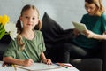 cute little child drawing with colored pencils and looking at camera while mother using digital Royalty Free Stock Photo