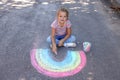 Cute little child drawing rainbow with colorful chalk on asphalt Royalty Free Stock Photo