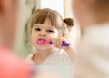 Cute child girl brushing teeth and looking in mirror in bathroom Royalty Free Stock Photo
