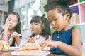 Cute little child girl with diversity friends eating cake together. kids eat dessert. Royalty Free Stock Photo