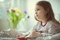 Cute little child girl ill sitting with tea in bed under blancket Royalty Free Stock Photo