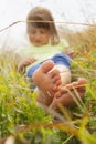 Cute little child girl  lie in a picturesque field with flowers and grass against a backdrop of hills and mountains. Happiness, Royalty Free Stock Photo