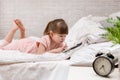Little child girl lies in bed uses digital tablet. Royalty Free Stock Photo