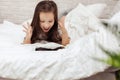 Little child girl lies in bed uses digital tablet. Royalty Free Stock Photo