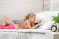 Little child girl lies in bed uses digital tablet. Royalty Free Stock Photo