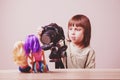 Cute little child girl photographer is shooting portrait of toys dolls  with a DSLR camera Royalty Free Stock Photo